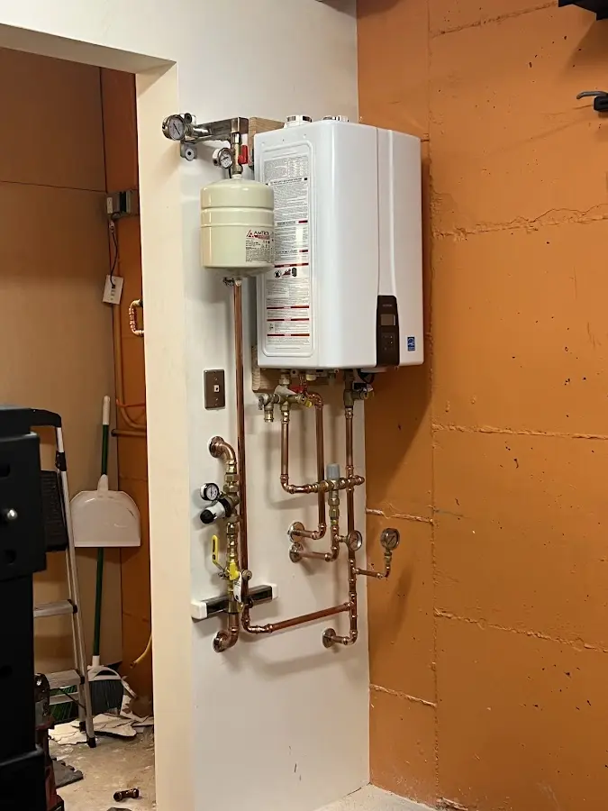 Plumbing technician inspecting water heater connections in Holton